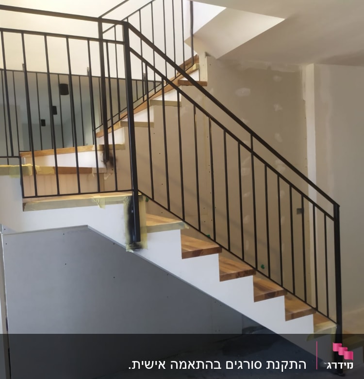 מעקה מתכת שחור על מדרגות עץ בבית